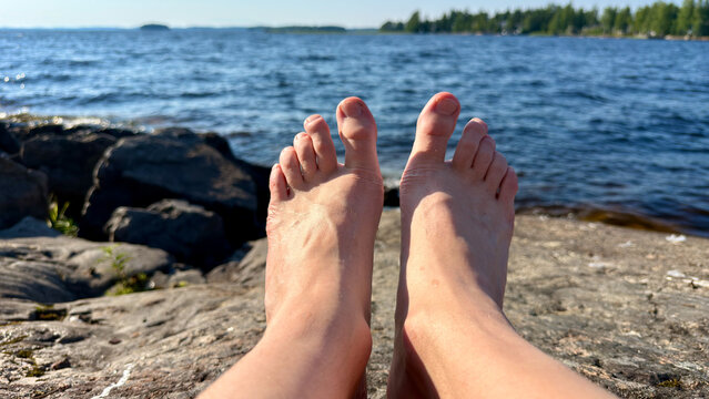 Bare Feet Resting on Lakeshore Rocks
