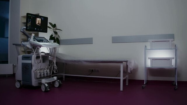 Empty modern ultrasound examination room with medical machine and patient bed