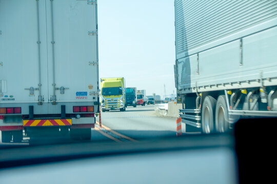 大型トラックの間を走行する普通自動車のイメージ