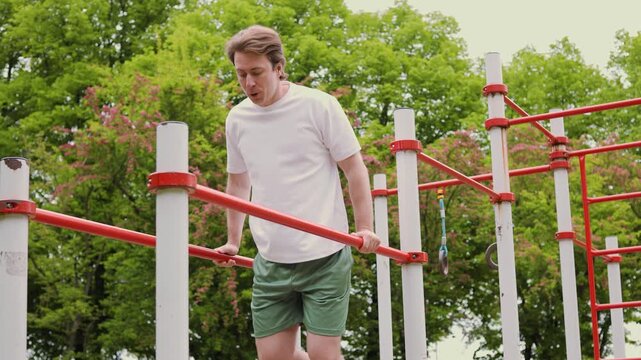 fit man doing a dips exercise on parallel bars during an outdoor workout in a park. His active training promotes health and fitness. High quality 4k footage