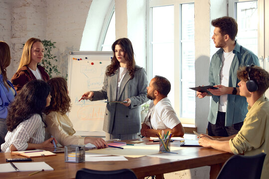 Business leader explaining strategy to creative team during office brainstorming session. Concept of strategic leadership, collaborative decision making, team development and business planning.
