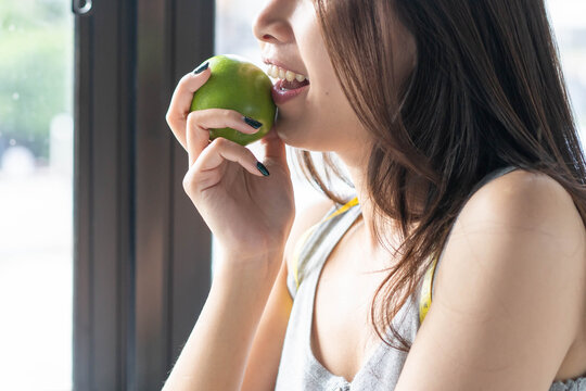 Healthy lifestyle concept with a beautiful girl eating organic fruit at home.