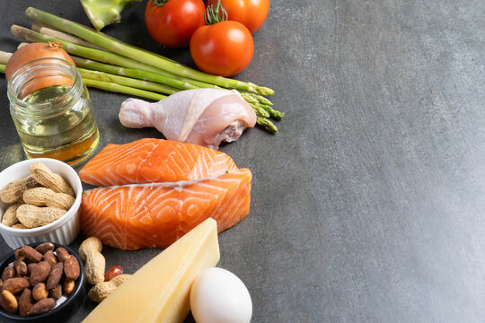 Ketogenic diet ingredients with salmon, chicken, eggs and vegetables on dark background with copy space
