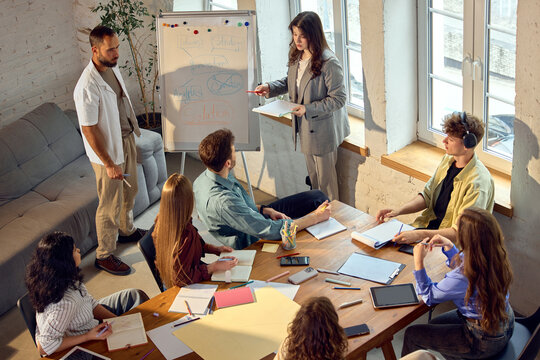 Diverse office team listening to female presenter during strategy meeting. Concept of strategic alignment, collaborative planning, idea presentation and effective team decision making.