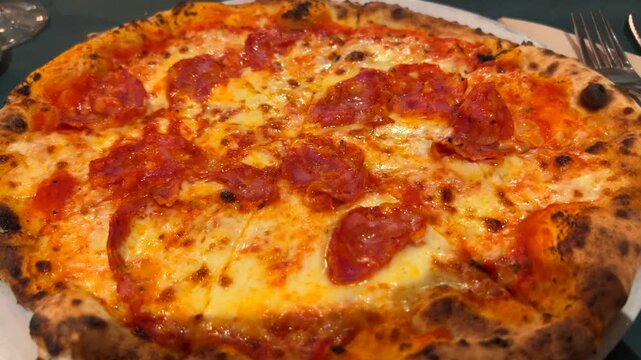 Freshly baked pepperoni pizza with melted cheese and crispy crust on round white plate.