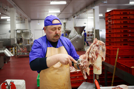 A man working at a butcher shop cuts up chicken carcasses. Dietary meat. Worker at a meat processing plant. Meat processing business concept