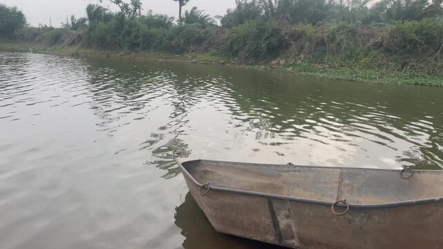 Small Metal Boat on Calm Lake with Scenic Rural Waterside Landscape