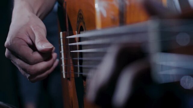 Detailed view of guitarist fingerpicking nylon strings on polished classical guitar