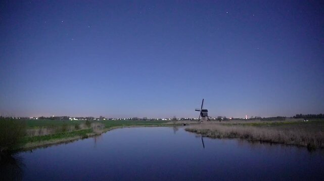 Broekmolen Windmill at Night Under a Starry Sky, Serene Landscape with Reflection in a Calm Canal, Netherlands.