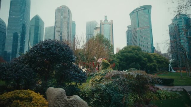 Ground-level shot of the Lujiazui Central Green park, Pudong, Shanghai, with ornamental shrubs, sculpted topiary, decorative rocks and a white sculpture in the foreground.