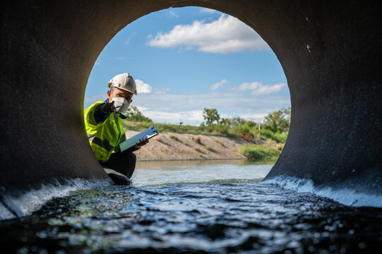 Environmental Technician Inspecting Water Flow in Concrete Culvert During Field Survey