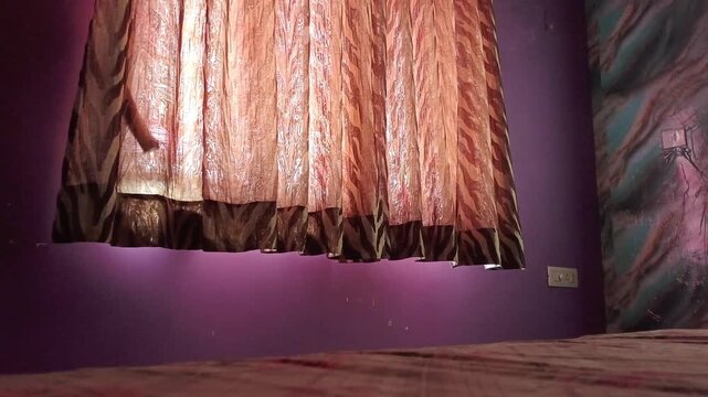 Sunlight streaming through elegant brown and orange pattern curtains in a purple bedroom interior