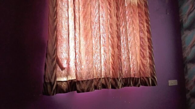 Sunlight streaming through elegant brown and orange pattern curtains in a purple bedroom interior