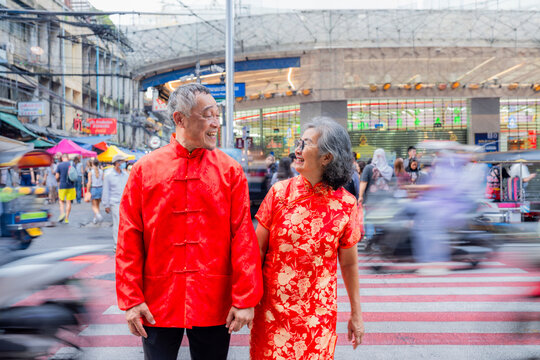 Couple walks hand in hand on a busy street in a city during a festive celebration
