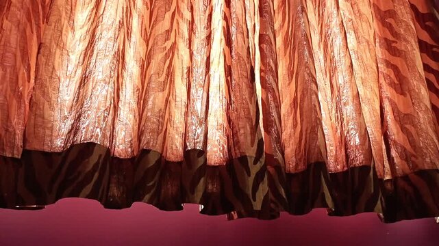 Sunlight streaming through elegant brown and orange pattern curtains in a purple bedroom interior