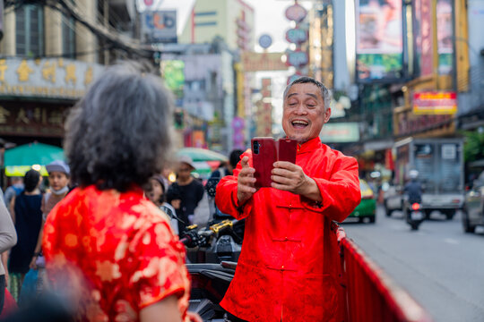 Couple takes selfie during festival celebration in busy city street at sunset