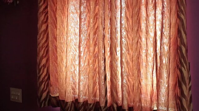 Sunlight streaming through elegant brown and orange pattern curtains in a purple bedroom interior