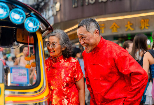 Elderly couple enjoying traditional attire while looking at street vendor in busy market