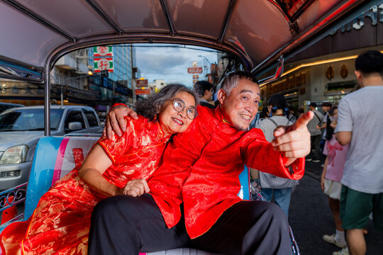 Couple enjoys a ride in a vehicle while celebrating a cultural event in a busy street during the evening