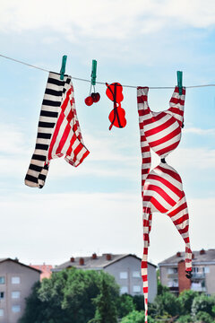 Swimsuit, cherries and red heart-shaped sunglasses hanging on a clothesline, urban summer concept