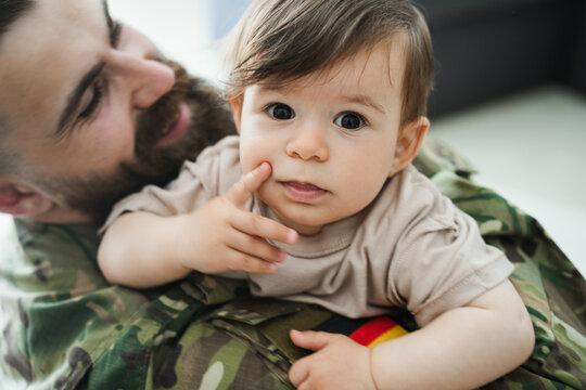 Male german soldier in military uniform hugs his little son at home - Emotional military happy homecoming concept - Soft focus on kid face