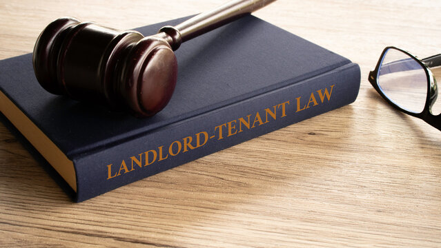 Landlord Tenant Law book with gavel and eyeglasses on wooden table
