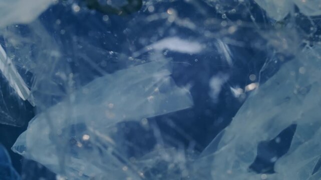 Abstract underwater shot of discarded plastic waste floating in blue water representing ocean pollution and environmental crisis.