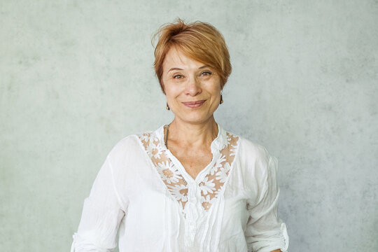 Indoor portrait of mature woman with a cute smile and natural look proudly showing her wrinkles representing authenticity healthy skin and a positive outlook on aging
