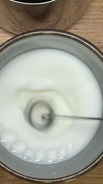 Whisking fresh milk with an electric frother