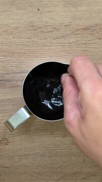 Hand stirring dark chocolate ganache glaze
