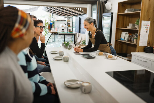 Multiracial people eating inside breakfast bar during morning time - Healthy food and morning lifestyle concept - Main focus on female waitress