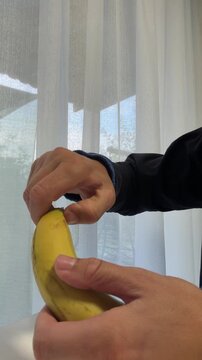 Person's hands peeling fresh yellow banana