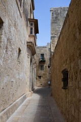Obraz premium Ancient narrow stone street with historic wooden balcony in a medieval european town.