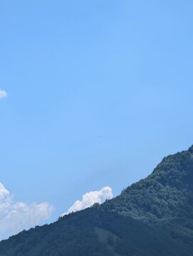 Inquadratura minimalista di un uccello solitario che vola alto nel cielo azzurro e limpido, sopra il profilo di una nuvola bianca. La clip evoca un senso di libert&agrave;