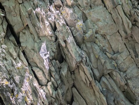 Inquadratura ravvicinata di una parete di roccia sedimentaria con evidenti strati e fratture geometriche