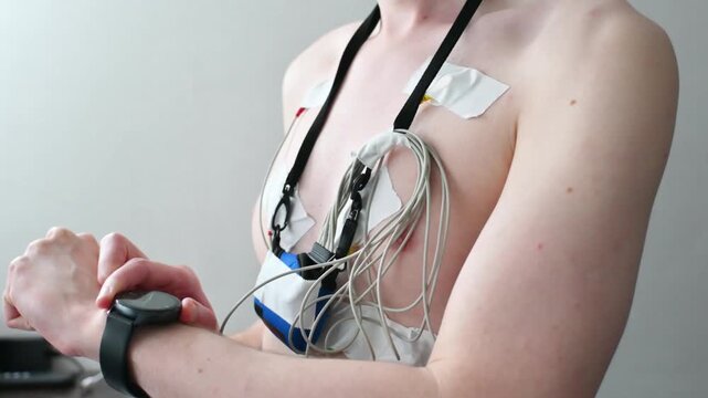 Person with ecg holter monitor electrodes on chest checks smartwatch.