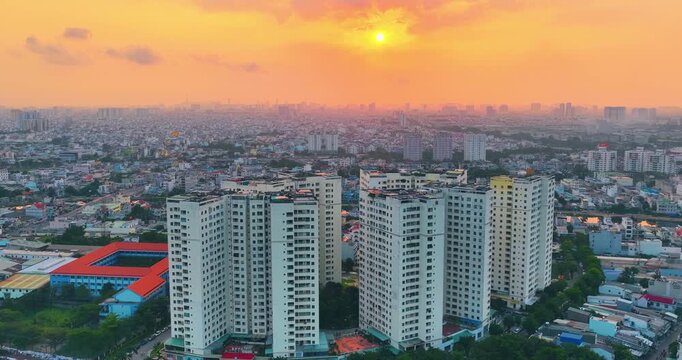 Sunrise over a residential district in Ho Chi Minh City, Vietnam. Warm golden light and morning haze illuminate high-rise apartment buildings and the sprawling urban landscape