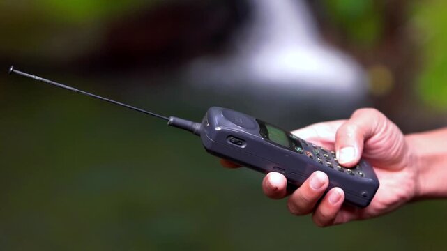 Operating a 90s mobile phone, a communication device that still relied on an antenna to pick up a signal.