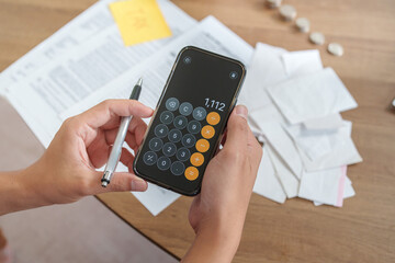 Cropped hands using calculator app on smartphone for tax planning
