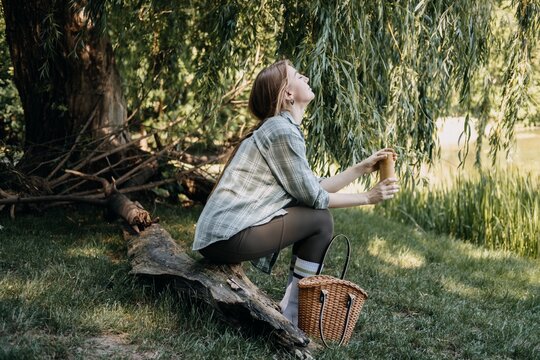 Young woman enjoying nature by a lake, mindful consumption, outdoor relaxation, picnic lifestyle, nature escape