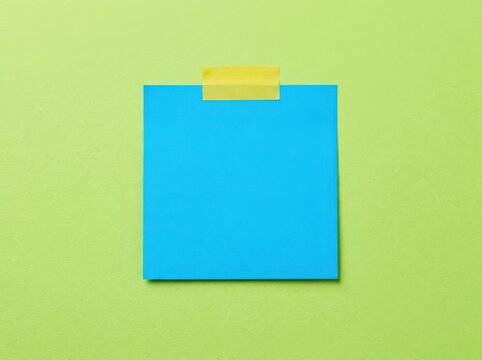 Blue square sticky note attached with yellow tape on a bright lime green surface for reminders and office communication tasks isolated on white background