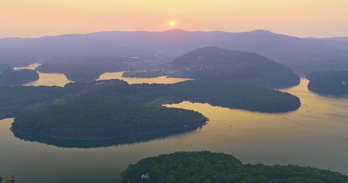 Peaceful sunset over Tuyen Lam Lake in Da Lat, Vietnam. Warm golden light reflects on the winding lake surrounded by pine-covered islands and rolling highland hills