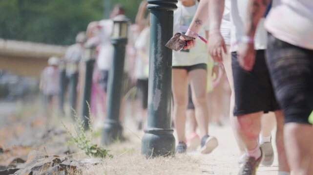 Participants walk along a path during a charity event by the water in sunny weather