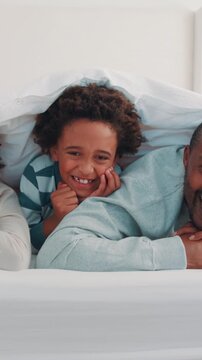 Happy, face and parents with kids with blanket for wake up, relax and comfortable for morning in home. Laugh, family and portrait of African boys, mom and dad for affection, love and weekend in bed