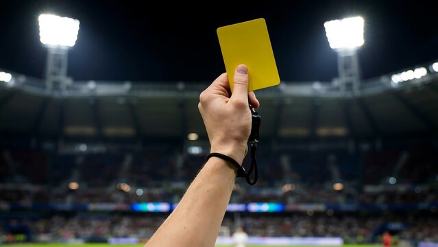 Referee holding yellow card in stadium