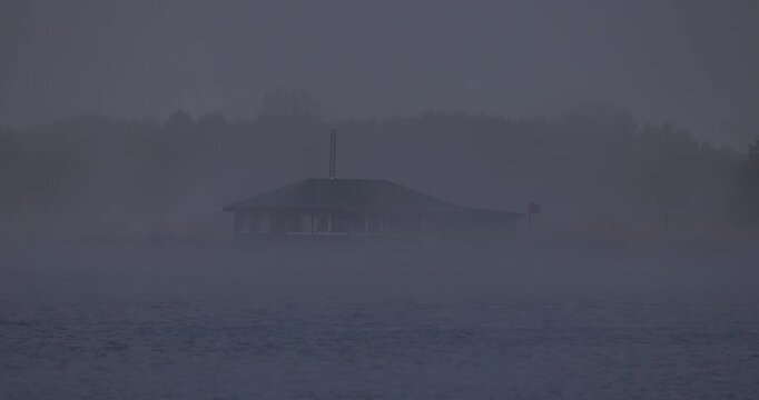 Distant view of one wooden stilt fishing house on a lake in thick fog