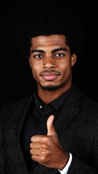 A young man giving a thumbs up in a professional setting with a black background