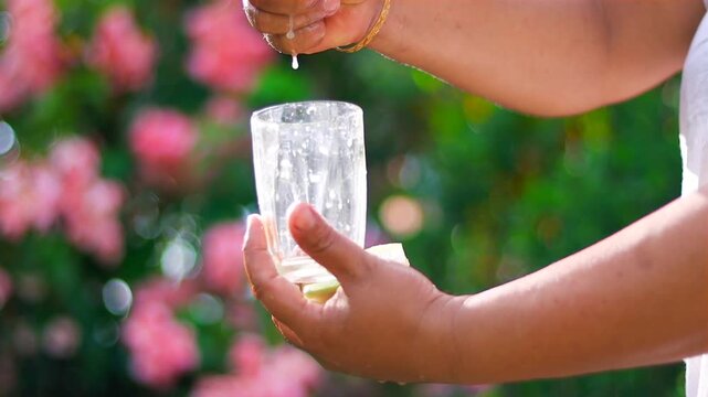 Fresh lime juice being squeezed into a clear glass outdoors, capturing vibrant citrus droplets in bright natural sunlight. Perfect for concepts of healthy drinks, freshness, and natural ingredients.