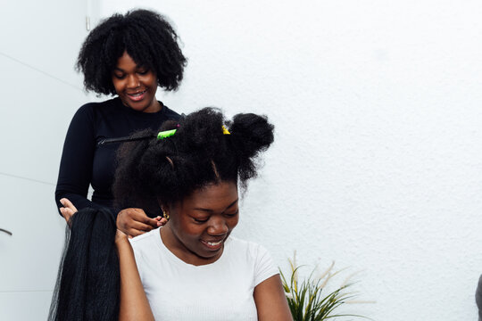 Woman getting hair braided at salon