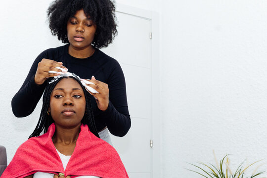 African american woman applying hair mousse to braids